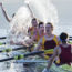 Rowing team splashing and celebrating in scull on lake