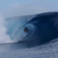 A surfer riding through the tunnel of a crashing wave